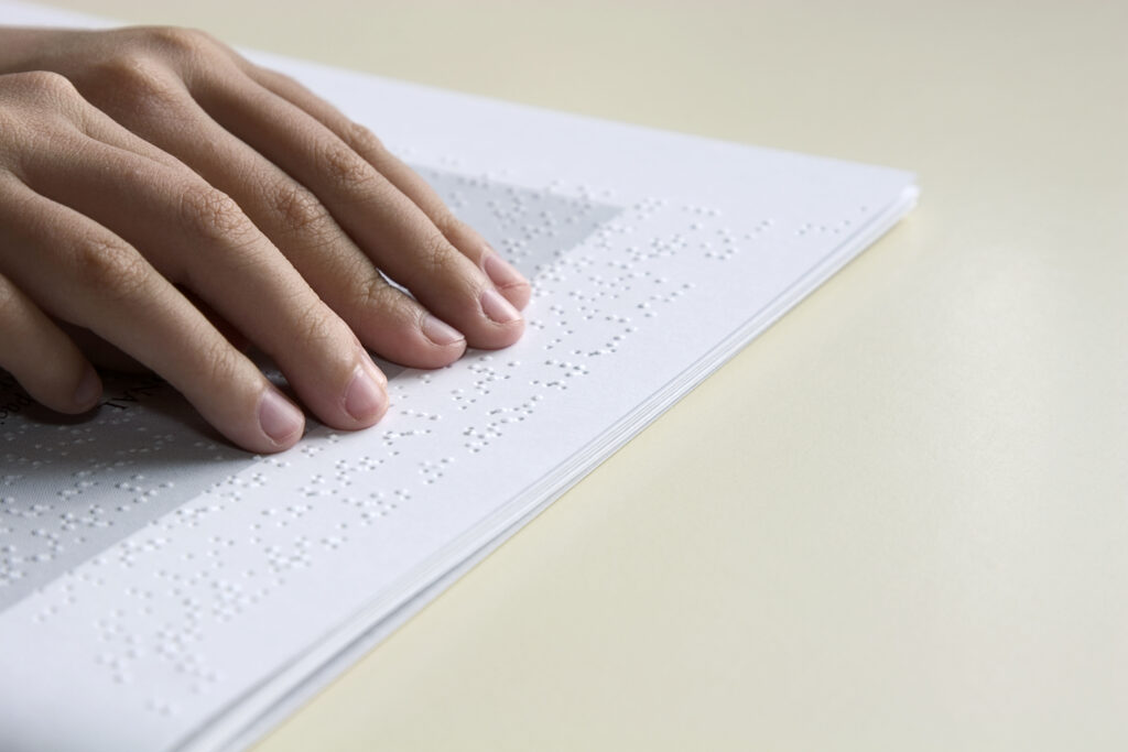 A hand going over a document in braille